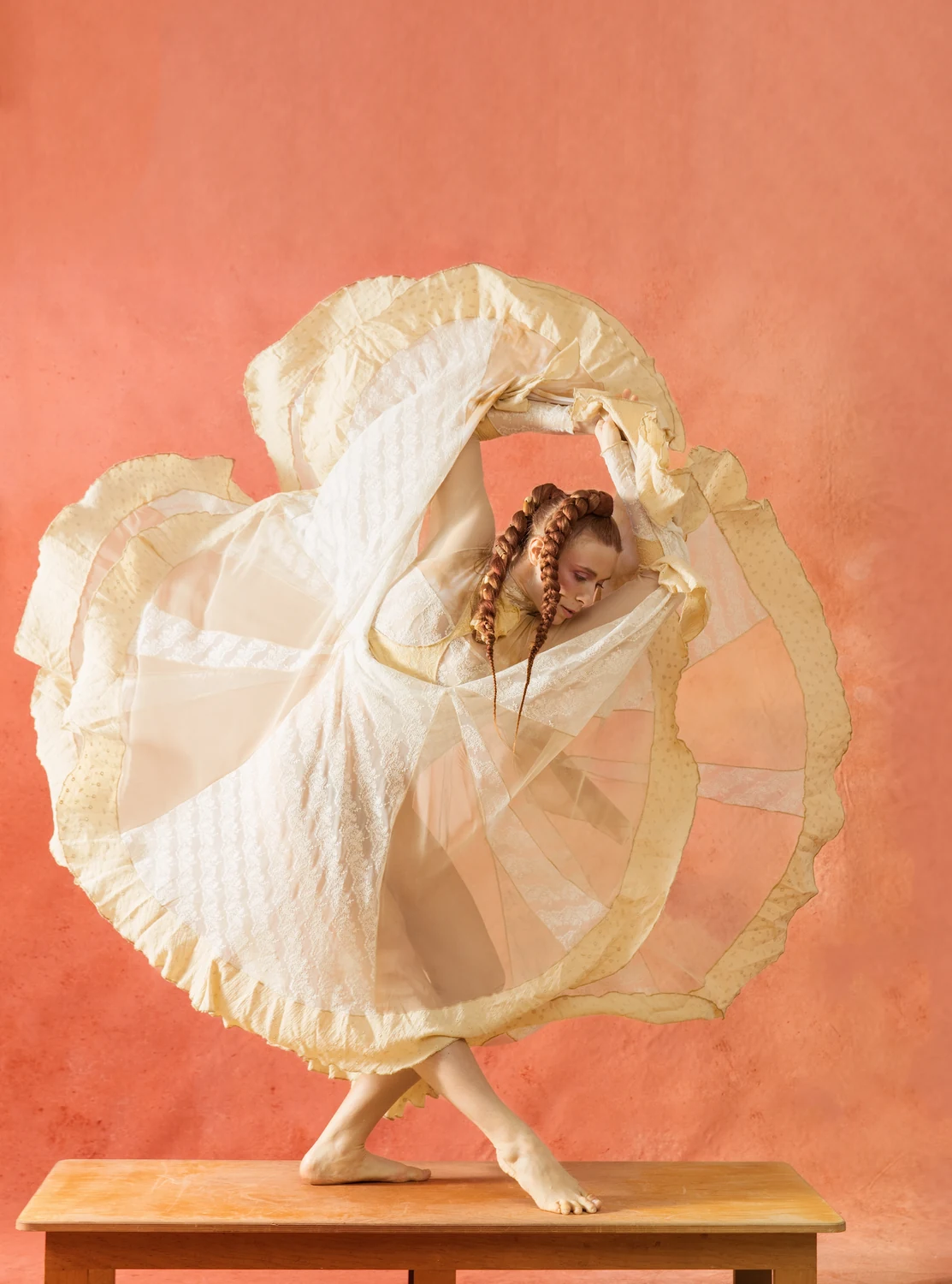 Performer framed by a circular sweep of cream skirt fabric on a low platform.