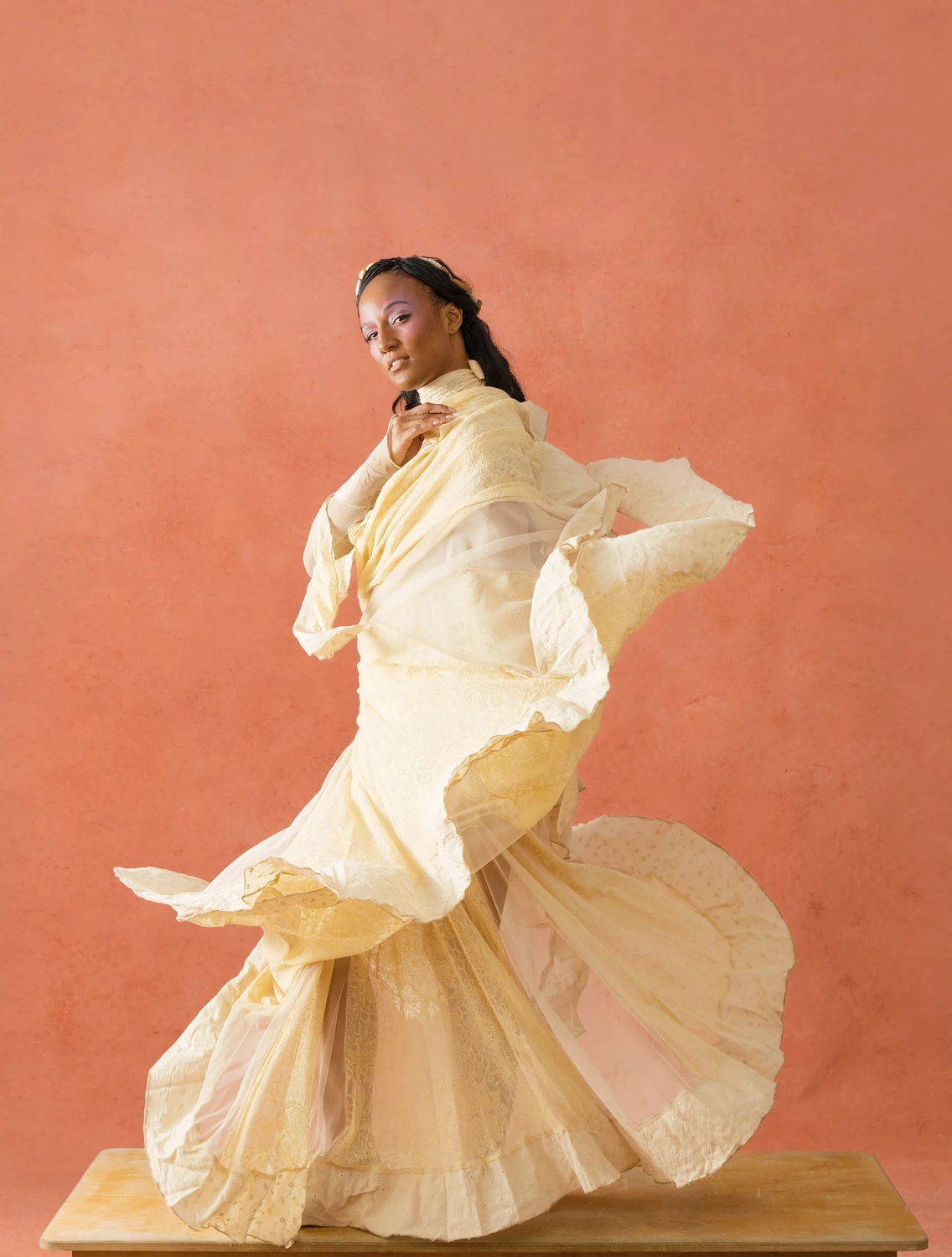 Performer turning in a layered cream dress with fabric trailing around the body.