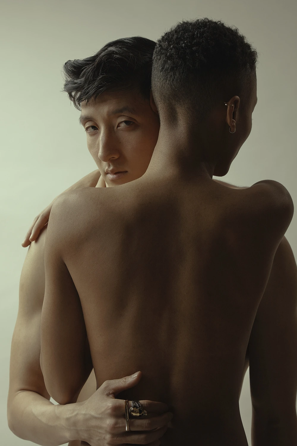 One person facing camera while held in a close back-to-camera embrace.