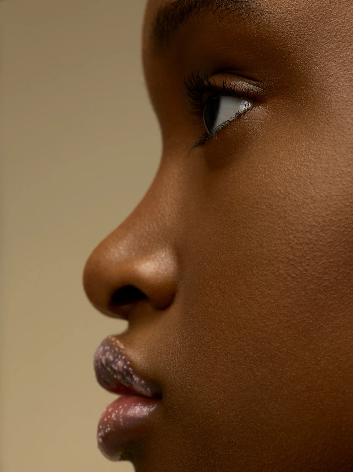 Close profile of dewy skin lit to emphasize natural sheen and softness
