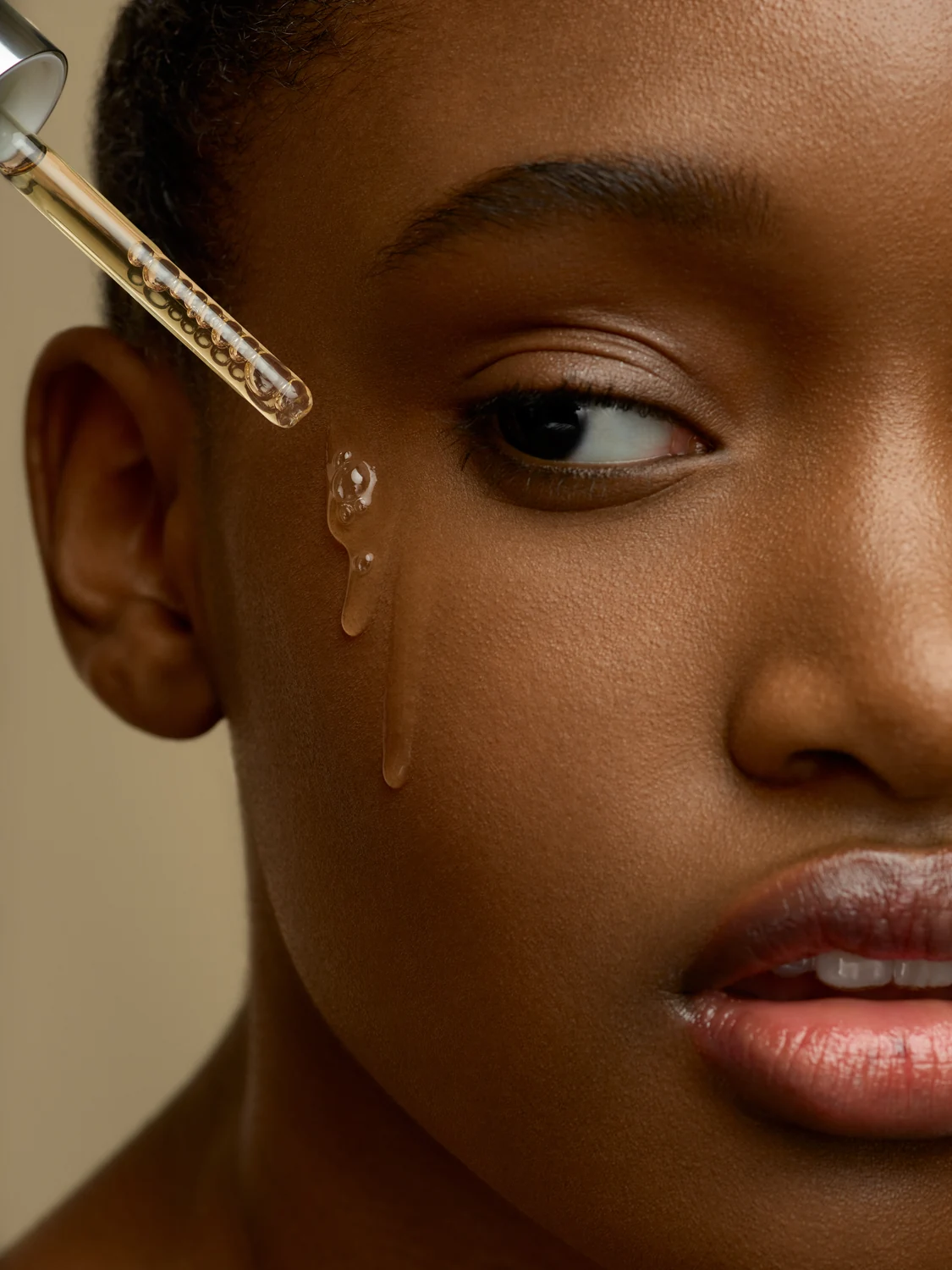 Serum dropper paired with a beauty portrait to connect face and product ritual