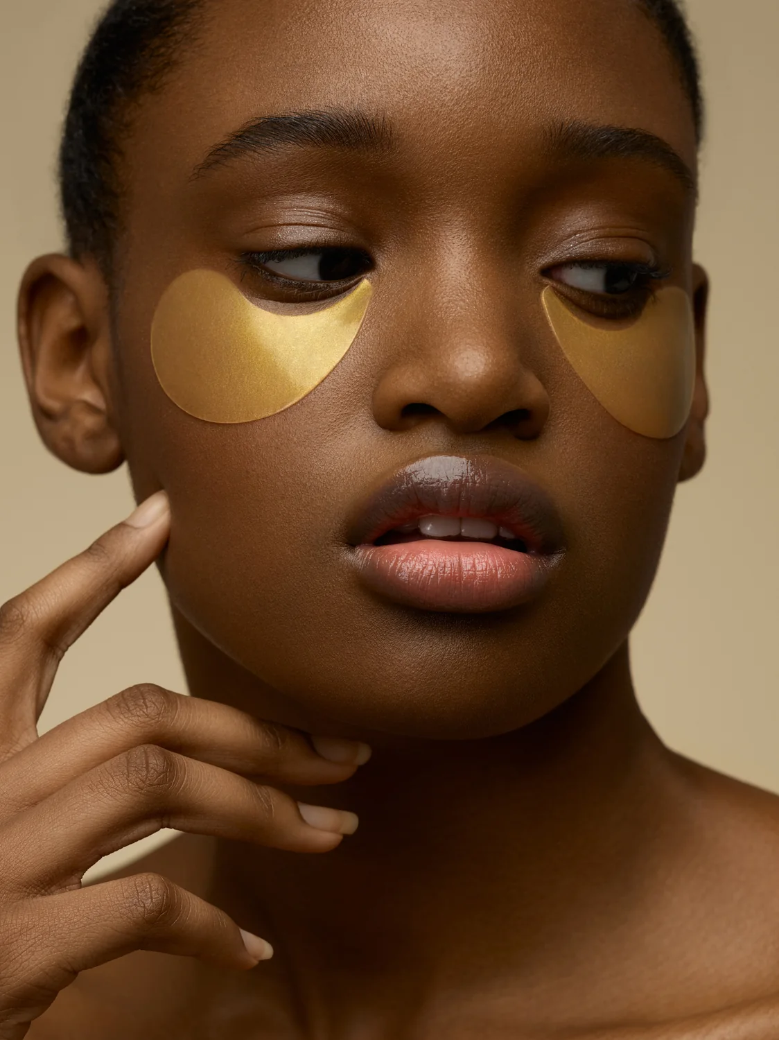 Beauty portrait with gold under-eye masks emphasizing reflective texture
