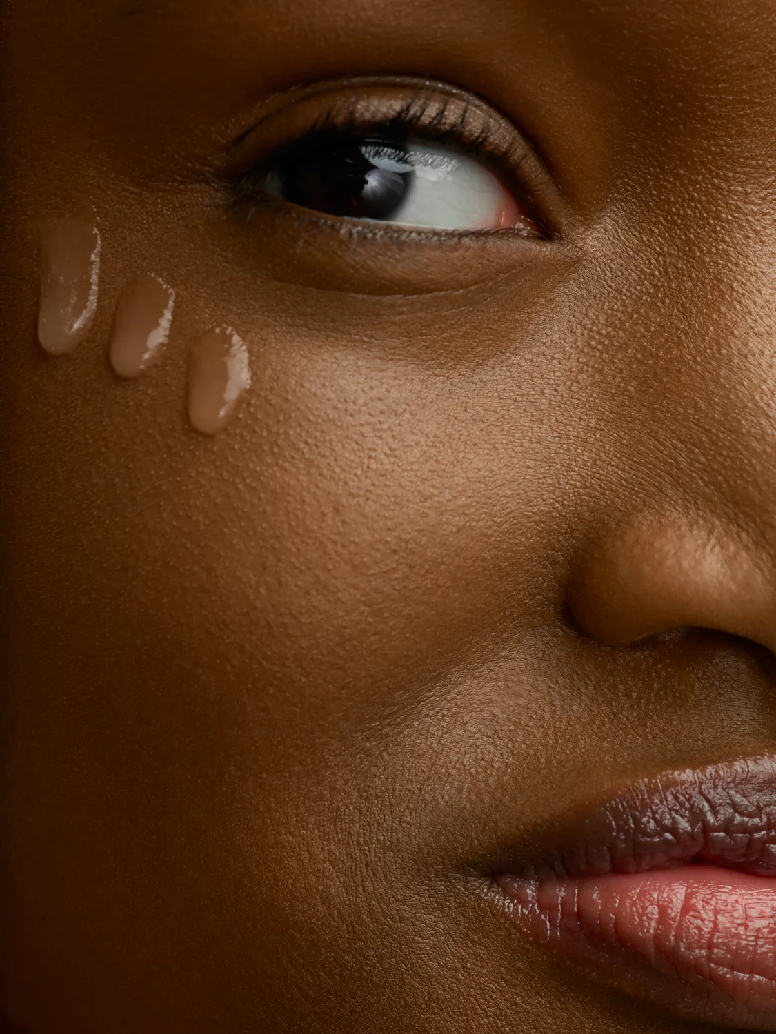 Clear serum drops on a cheek highlighting skin texture and transparency